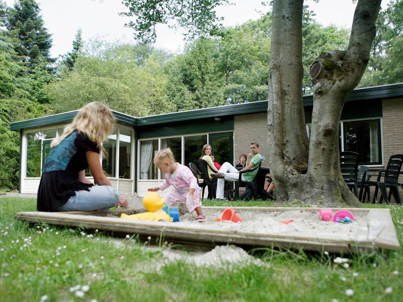 Een leuke achtertuin met een zandbak.