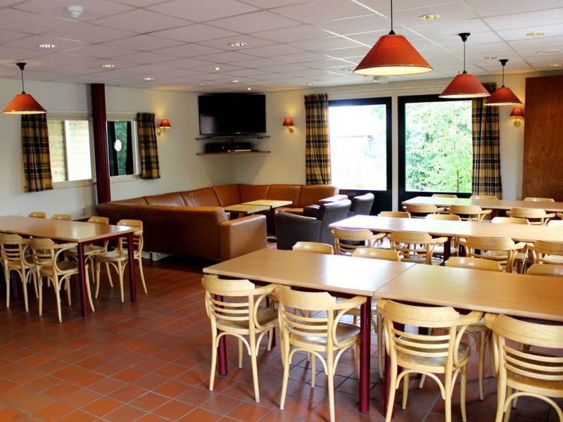De eetzaal met houten tafels en stoelen.